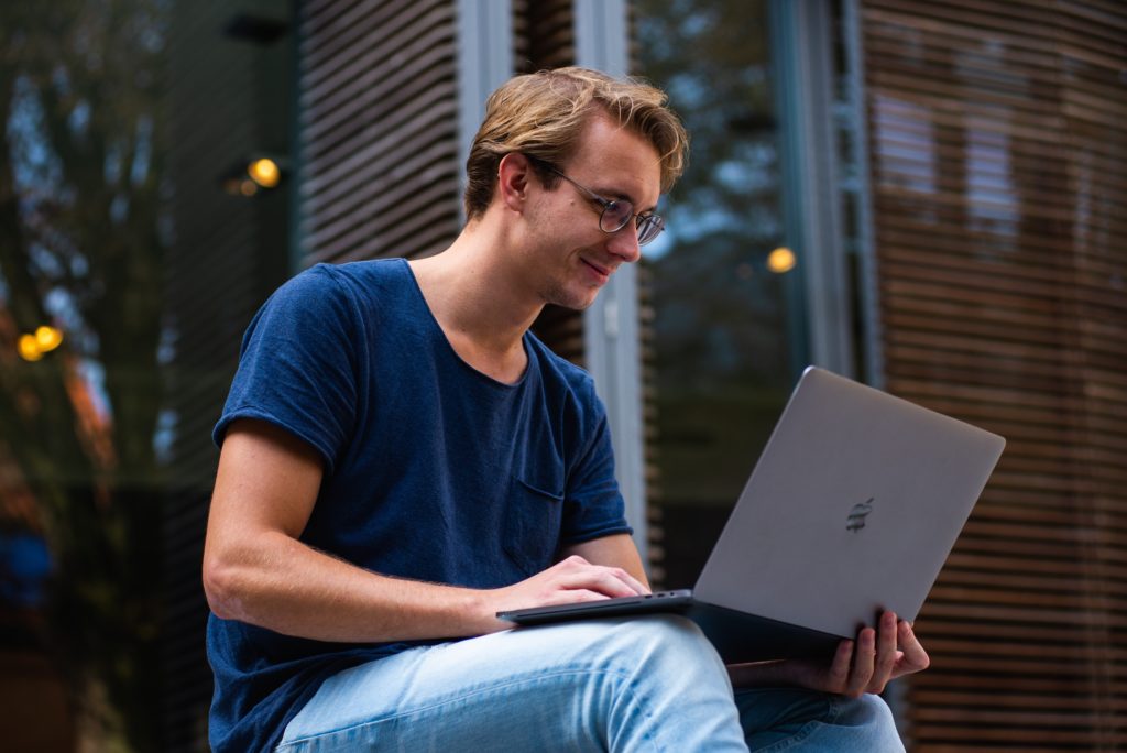 Young adult man looking at his laptop and smiling